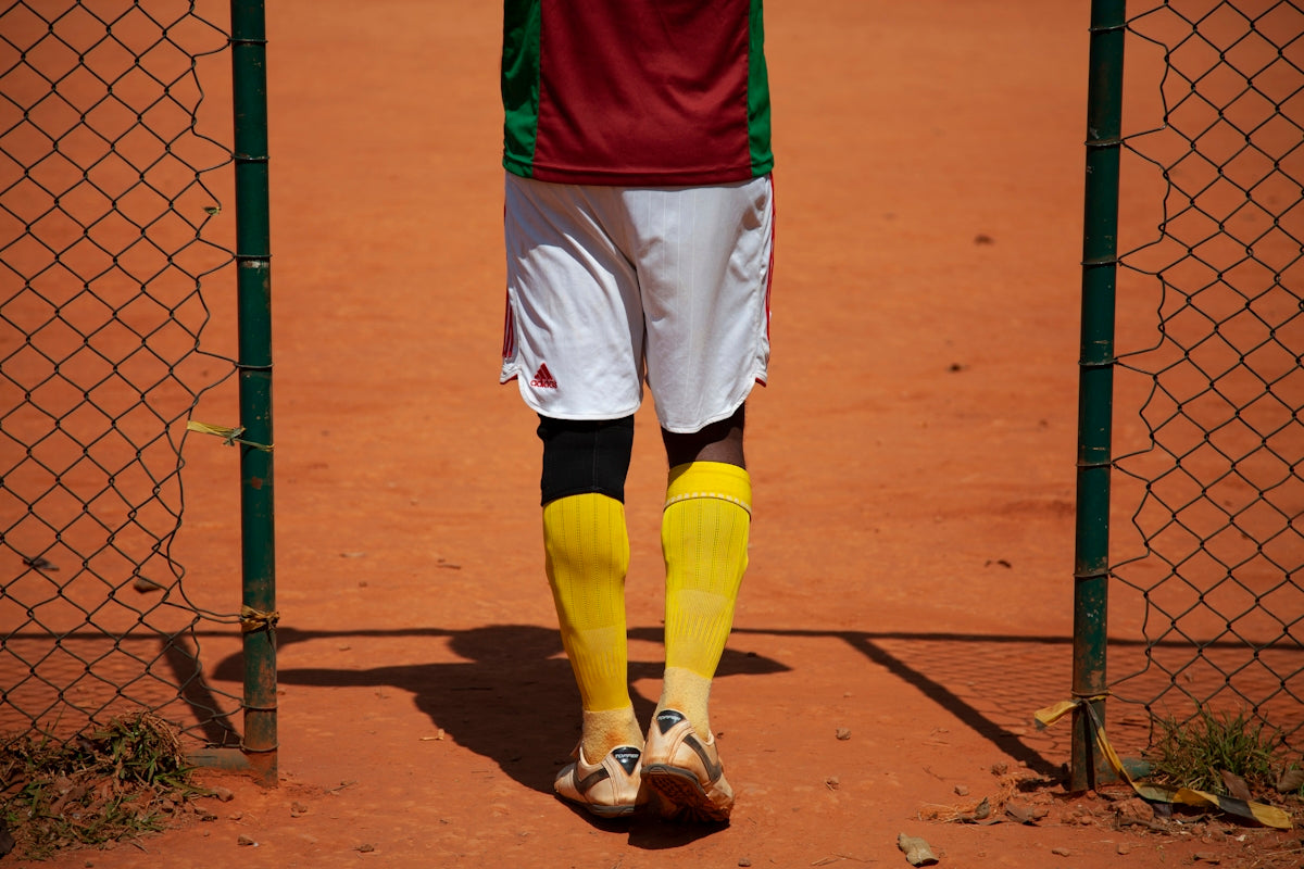 person in red shirt and yellow shorts standing on brown field