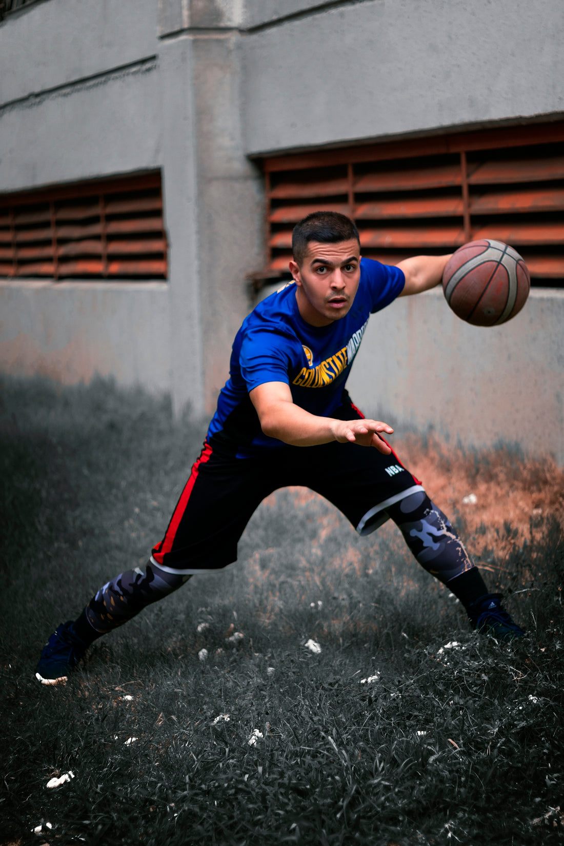 a young man holding a basketball on top of a field