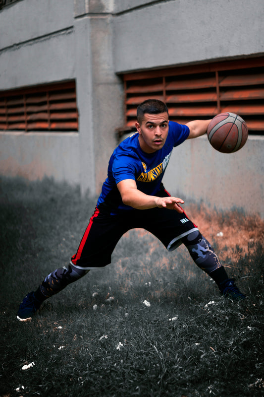 a young man holding a basketball on top of a field
