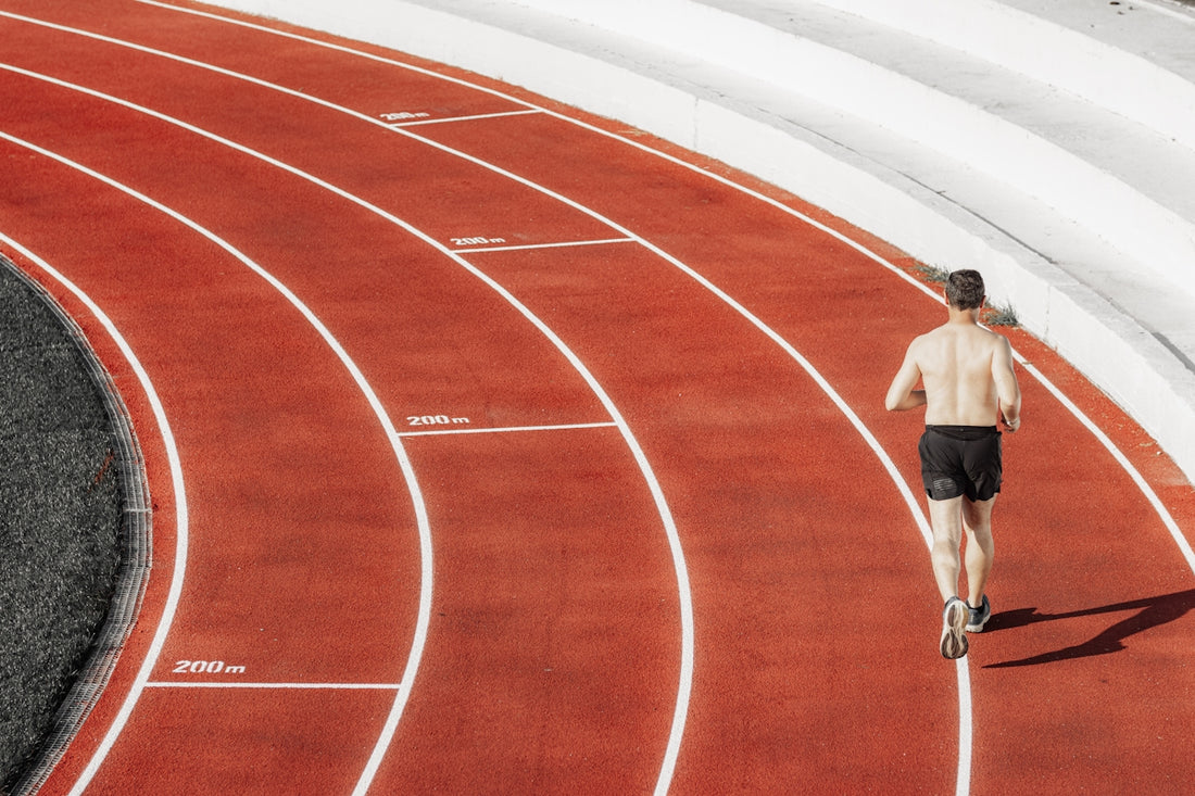 Man running on a red track with white lines.