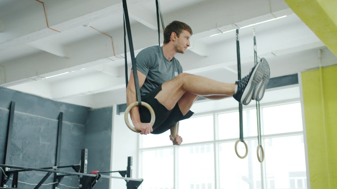 Man performing exercise on gymnastic rings in gym.