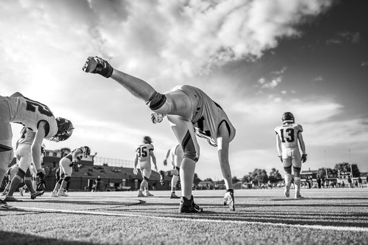 American football players stretching on field during game.