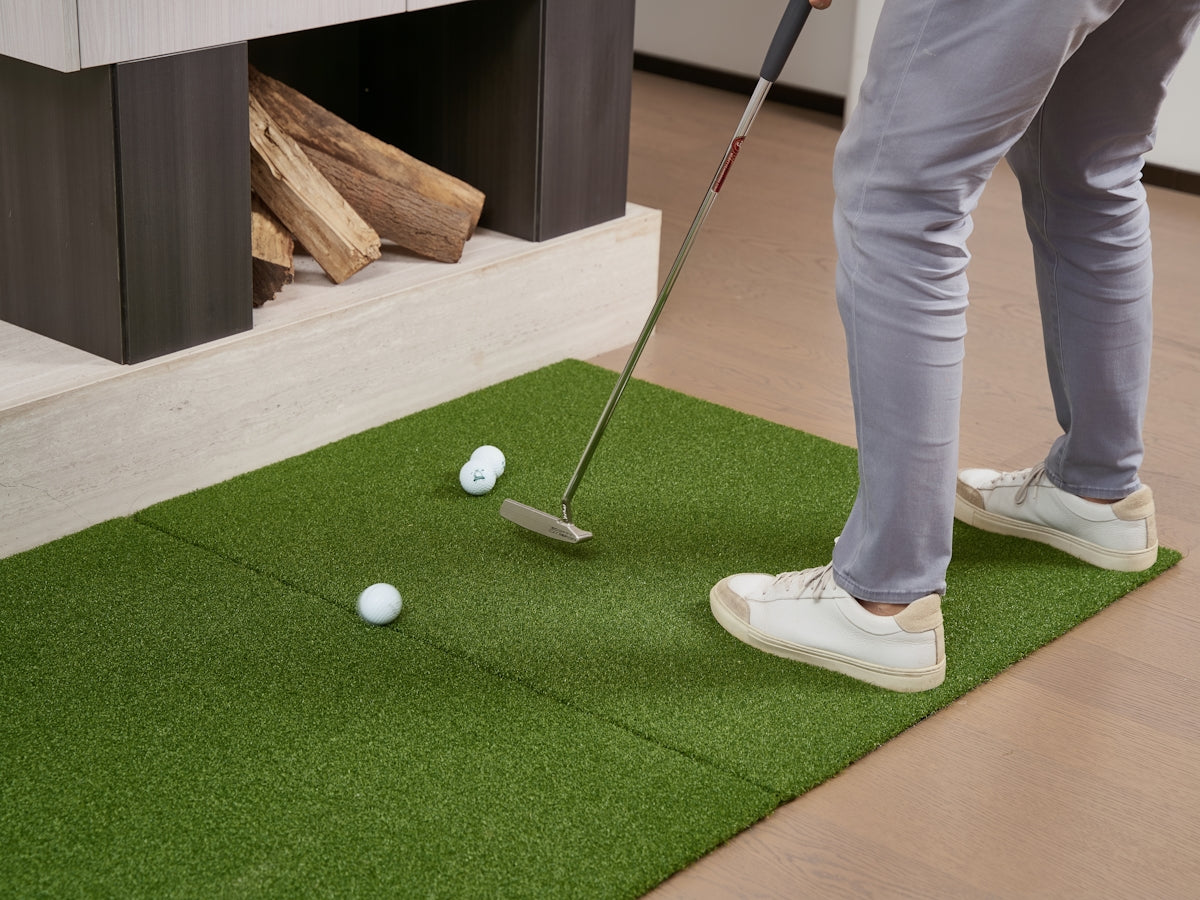 Person practicing golf putt on indoor putting green.