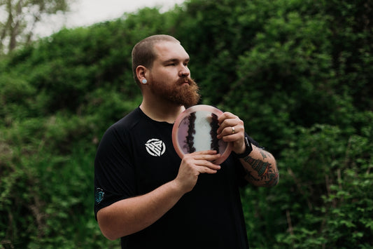 Man holding a disc golf disc outdoors